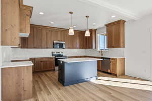Kitchen featuring stainless steel appliances, pendant lighting, tasteful backsplash, light wood-style floors, and recessed lighting