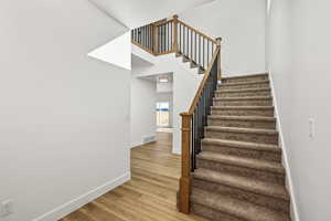 Stairway with wood finished floors and a towering ceiling