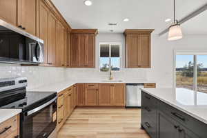 Kitchen featuring stainless steel appliances, hanging light fixtures, plenty of natural light, light wood-style floors, and recessed lighting
