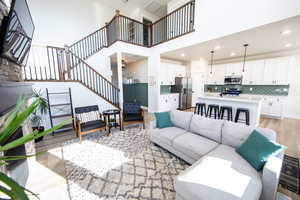 Living room featuring light wood finished floors, a high ceiling, stairs, and recessed lighting
