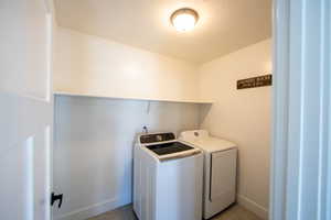 Laundry area featuring a textured ceiling and washing machine and clothes dryer
