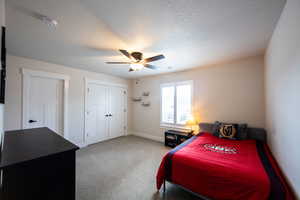 Bedroom with light carpet, a textured ceiling, ceiling fan, and a closet