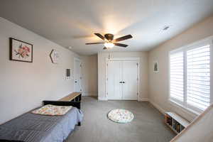 Carpeted bedroom featuring a closet, a textured ceiling, and ceiling fan