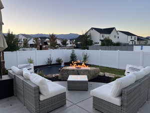 Patio terrace at dusk featuring an outdoor living space with a fire pit, a patio area, and a residential view