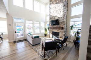 Living area with light wood finished floors, a fireplace, plenty of natural light, and a high ceiling