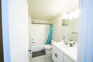 Bathroom with shower / bath combo with shower curtain, vanity, light tile patterned floors, and a textured ceiling