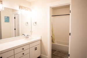 Bathroom with vanity, shower / bath combination with curtain, and dark tile patterned flooring