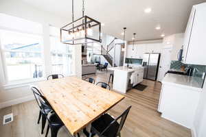 Dining area featuring stairway, light wood-style floors, recessed lighting, and a chandelier