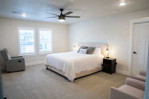 Bedroom with carpet flooring, a ceiling fan, and a textured ceiling