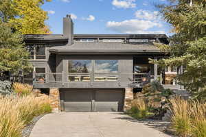 View of front of home featuring a chimney, concrete driveway, and a garage