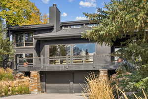 View of front of property with a chimney, an attached garage, driveway, stucco siding, and a shingled roof