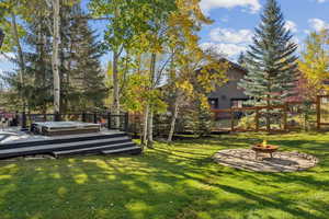 View of yard featuring a fire pit, a wooden deck, and view of wooded area