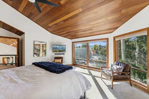 Bedroom with vaulted ceiling, light colored carpet, wooden ceiling, and a ceiling fan