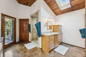 Bathroom with a skylight, vanity, wooden ceiling, finished concrete floors, and a shower stall
