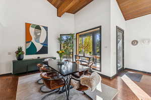 Dining room featuring a wood ceiling with exposed beams, wood finished floors, and high vaulted ceiling