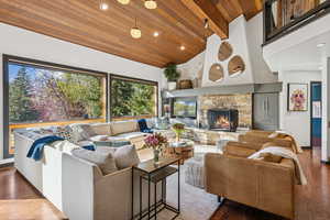 Living room with wood finished floors, high vaulted ceiling, wood ceiling, recessed lighting, and a fireplace