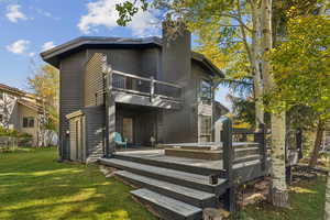 Rear view of house featuring a chimney, a deck, and a balcony
