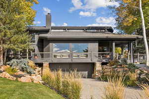 View of front facade featuring a chimney, concrete driveway, and a garage