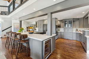 Kitchen featuring gray cabinets, glass insert cabinets, wine cooler, dark wood finished floors, and recessed lighting