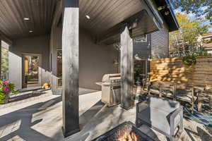 View of patio featuring a wooden deck, outdoor dining area, an outdoor fire pit, and a grill