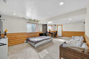 Bedroom featuring carpet flooring, rustic walls, multiple windows, recessed lighting, and a textured ceiling