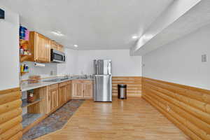 Kitchen with open shelves, light wood-style floors, appliances with stainless steel finishes, a textured ceiling, and recessed lighting