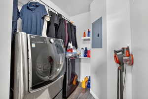 Washroom featuring dark wood-style flooring, electric panel, and washer and clothes dryer