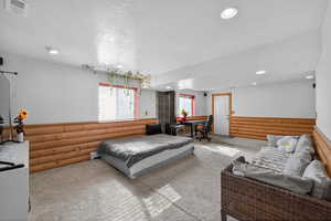 Bedroom featuring carpet floors, log walls, recessed lighting, and a textured ceiling