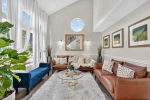 Living room with high vaulted ceiling, plenty of natural light, wood finished floors, and stairway