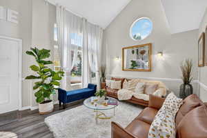 Living area with healthy amount of natural light, high vaulted ceiling, and dark wood-style floors