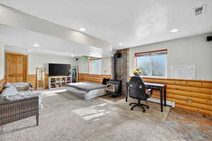 Bedroom with a textured ceiling, carpet, a wood stove, recessed lighting, and a baseboard radiator