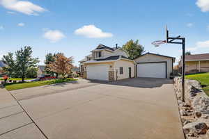 View of property exterior featuring a garage, an outdoor structure, concrete driveway, and stone siding