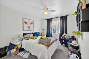 Bedroom featuring carpet, a textured ceiling, and a ceiling fan