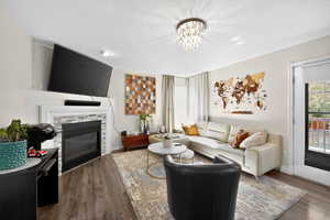 Living room featuring a fireplace, dark wood-style flooring, a textured ceiling, and a chandelier