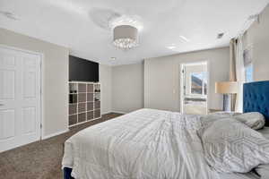 Bedroom with carpet floors, a textured ceiling, and a chandelier