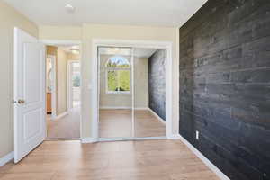 Doorway with wooden walls, wood finished floors, and an accent wall