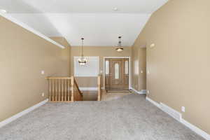 Tiled entrance foyer with carpet, a chandelier, and lofted ceiling