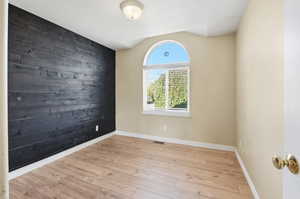 Empty room featuring wooden walls, wood finished floors, and an accent wall