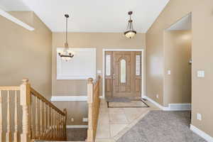 Carpeted entrance foyer with tile patterned flooring and baseboards