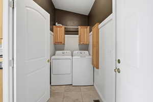 Laundry room featuring cabinet space, light tile patterned floors, washer and clothes dryer, and a textured ceiling