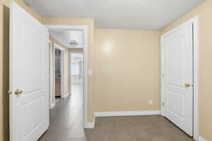Corridor with a textured ceiling and tile patterned floors
