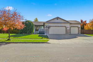 Single story home featuring a front lawn, concrete driveway, an attached garage, covered porch, and brick siding