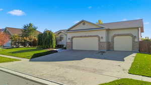 View of front facade with driveway, a front yard, a garage, and brick siding