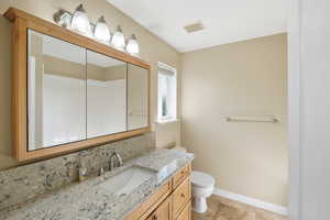 Bathroom featuring tasteful backsplash, vanity, and light tile patterned flooring