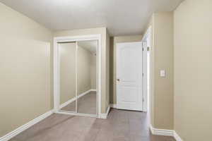 Unfurnished bedroom featuring a textured ceiling, a closet, and light tile patterned floors