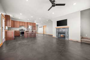 Kitchen with light countertops, open floor plan, appliances with stainless steel finishes, recessed lighting, and brown cabinets