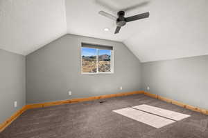 Additional living space featuring a textured ceiling, vaulted ceiling, carpet floors, and a ceiling fan
