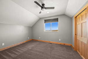 Bonus room featuring a textured ceiling, lofted ceiling, carpet flooring, and a ceiling fan