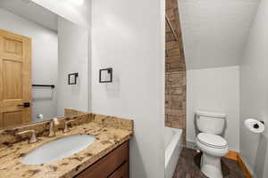 Full bath featuring vanity, a textured ceiling, dark wood finished floors, and shower / bath combination
