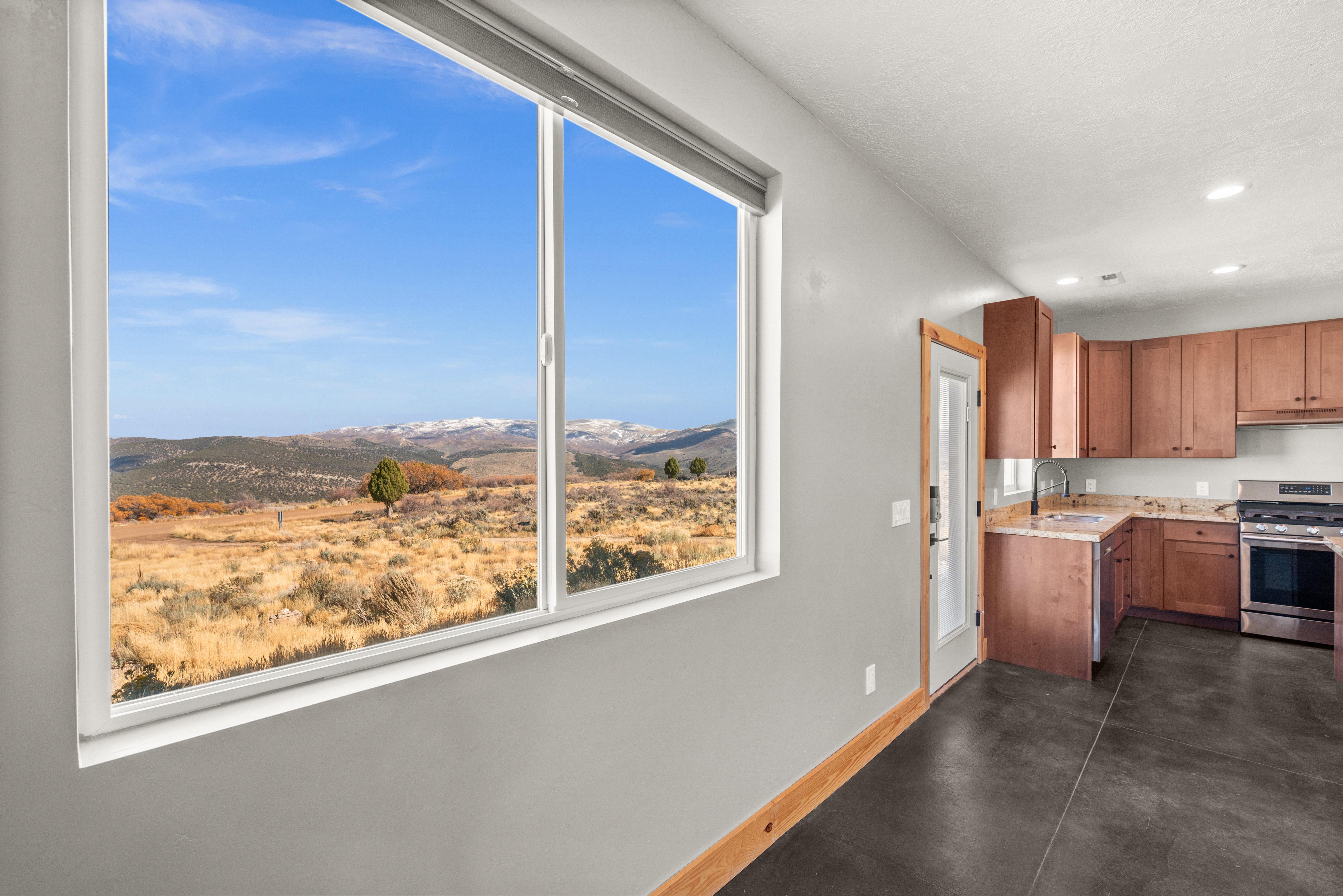 Kitchen with stainless steel range with gas stovetop, a mountain view, brown cabinets, recessed lighting, and concrete flooring